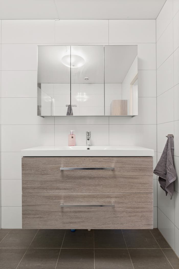 Stylish bathroom with wooden vanity, mirror, and white tiles.