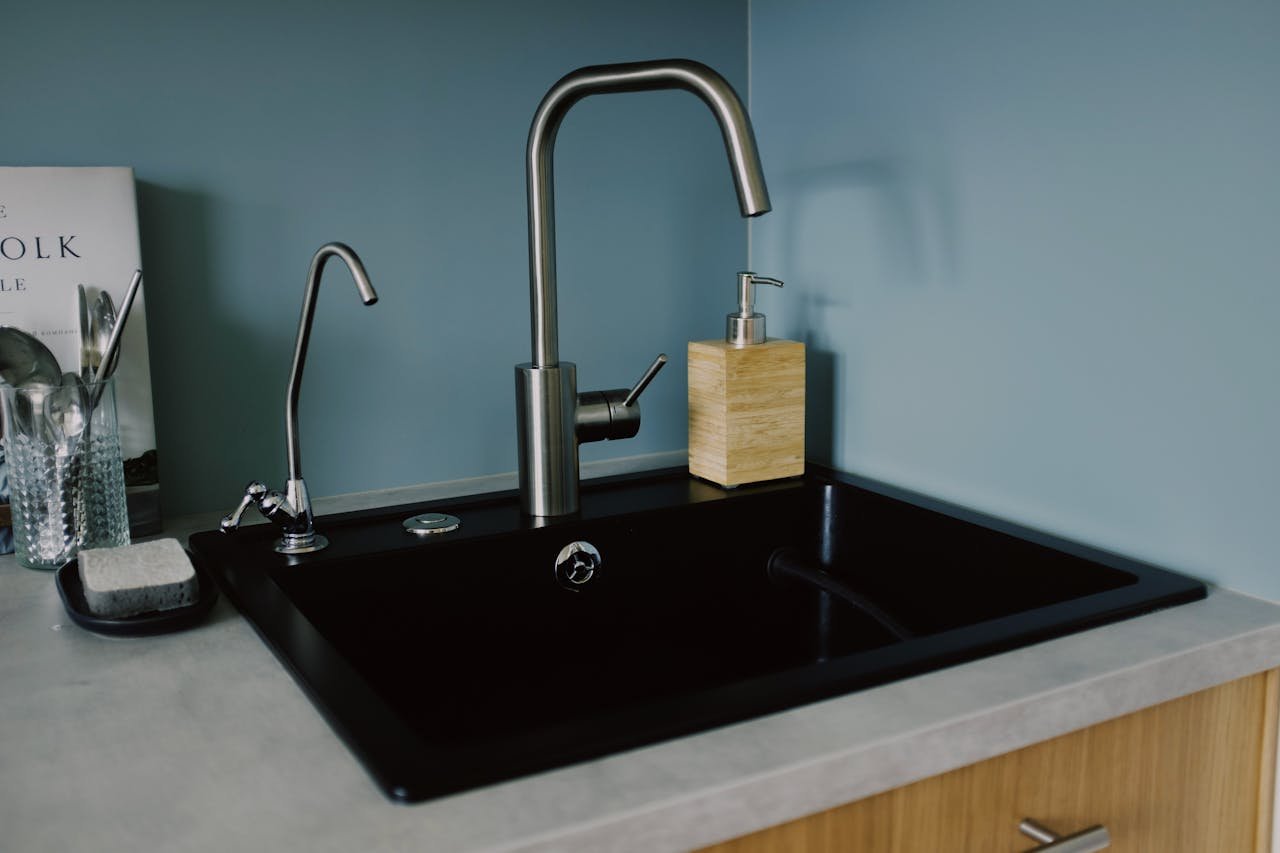 Stylish kitchen sink with faucet and soap dispenser in a minimalist setting.